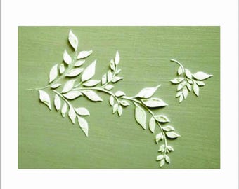 May include: White, three-dimensional leaf sprigs on a green background. The leaves are arranged in a natural, organic pattern, with a few separate sprigs scattered around the main arrangement. The leaves have a textured appearance.