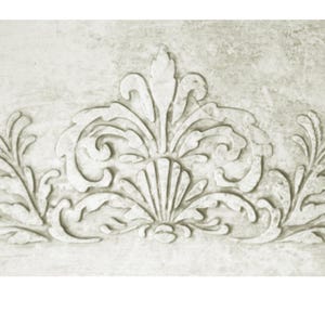 May include: A detailed, off-white decorative relief with a symmetrical floral design. The central element resembles a stylized shell, flanked by scrolling leaves and flourishes. The textured surface adds depth to the ornate, classical-style artwork.