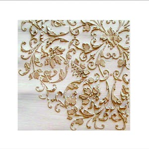 May include: Close-up of a light-colored wooden surface with an embossed floral design. The design features swirling vines, leaves, and flower-like shapes in a warm, golden hue. The intricate details create a textured, decorative pattern.