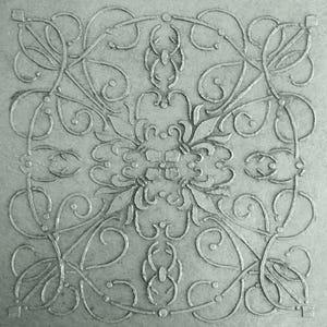 May include: A square, gray decorative tile with an embossed floral and scroll design. The symmetrical pattern features stylized leaves, vines, and swirling lines, creating an elegant, textured surface. The tile's design is reminiscent of classic art.