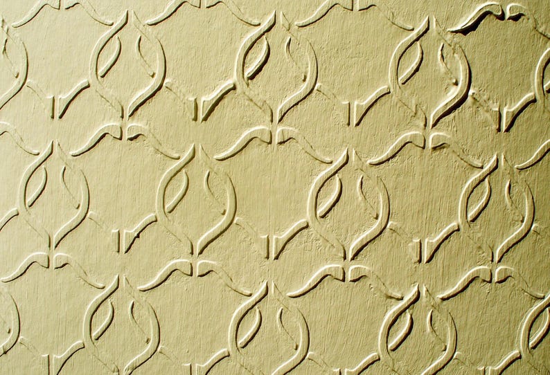 Puede incluir: Primer plano de una superficie texturizada de color amarillo claro con un patr&oacute;n repetitivo de formas curvas y estilizadas. El patr&oacute;n est&aacute; en relieve, creando sombras y profundidad, y el efecto general es decorativo.