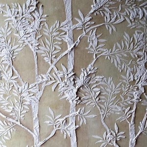 May include: White textured relief art of trees with detailed leaves against a beige background. The artwork features a repeating pattern of tree trunks and branches, creating a natural, organic design. The raised texture adds depth and dimension to the piece.