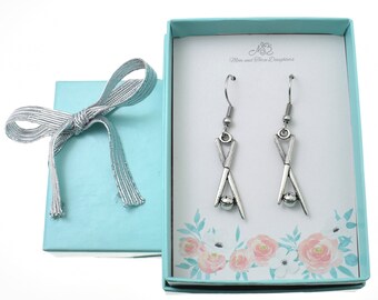 May include: A pair of silver earrings in a light blue gift box with a silver ribbon. The earrings are shaped like a pair of drumsticks with a small silver ball at the end of each drumstick. The box has the text "M&3 Mom and Three Daughters" printed on the inside.