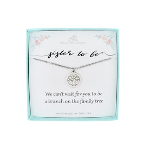 May include: A silver necklace with a tree pendant in a light blue box. The box has a white card with the text "sister to be" and "We can't wait for you to be a branch on the family tree".