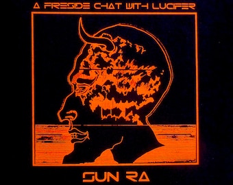 May include: A black t-shirt with an orange graphic of a demon's head with horns and the text "A Fireside Chat With Lucifer" and "Sun Ra" printed on the front.