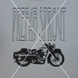 May include: A green t-shirt with a black graphic of a motorcycle and the text "PREFAB SPROUT" printed on the back.