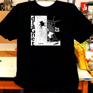May include: Black t-shirt with a white graphic of a spider web, a spider, and the text "dragnet" and "The Fall" with the year "1979" below.