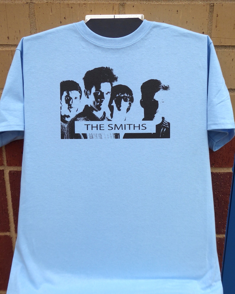 May include: Light blue t-shirt with a black and white image of the band The Smiths. The image features five band members in silhouette.