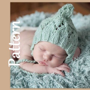 Puede incluir: Un gorro de bebé de punto suave azul claro con una parte superior puntiaguda y un delicado patrón de punto. El gorro lo lleva un bebé dormido sobre una manta peluda azul claro.