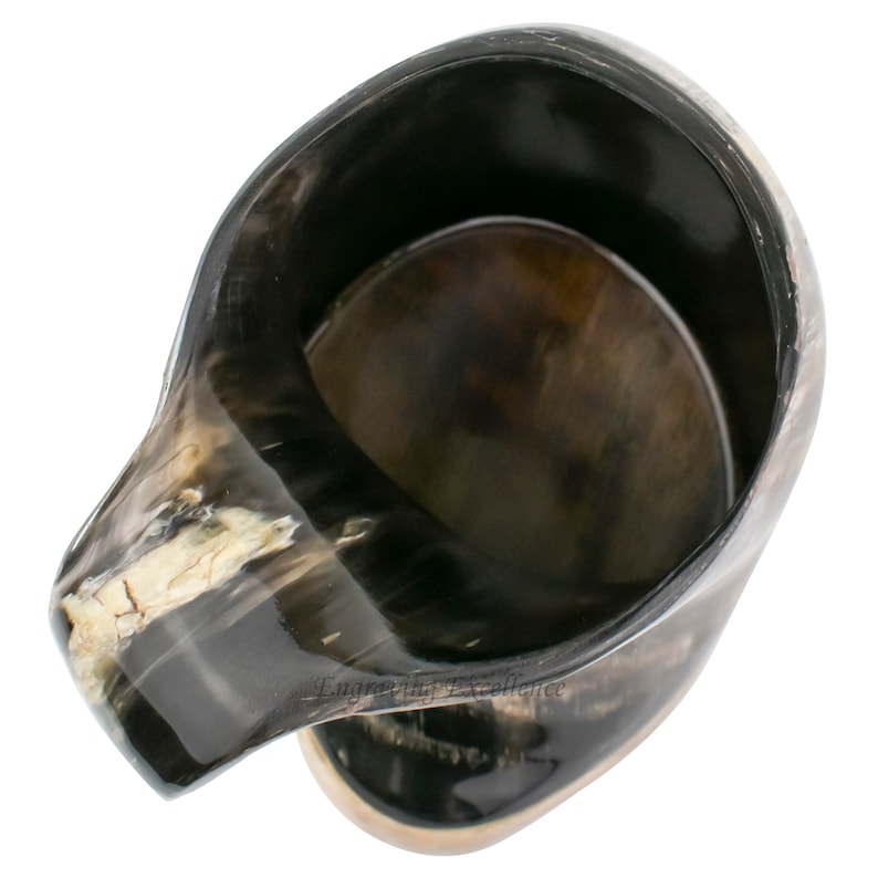 May include: A black and brown drinking horn with a handle. The horn is made of natural material and has a smooth, polished finish.