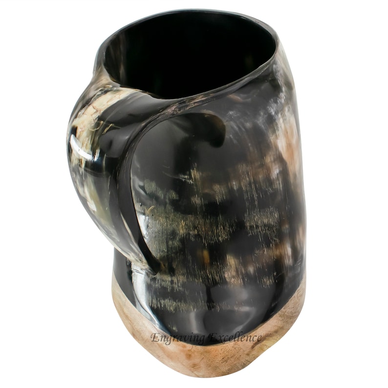 May include: A black and brown drinking horn mug with a handle. The mug is made of polished horn and has a natural, rustic look.