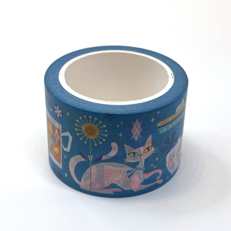 May include: A roll of blue washi tape with a repeating pattern of a cat, a flower, a cup, and stars.