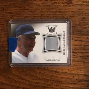 May include: A SportKings Volume No. 2 single memorabilia card featuring a portrait of Walter Alston in a protective case. The card has a gray and white design with the text "SINGLE MEMORABILIA".