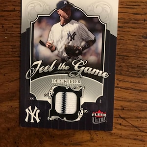 Puede incluir: Tarjeta de béisbol con Derek Jeter con el uniforme de los Yankees de Nueva York. La tarjeta tiene un parche y el texto "Feel the Game". La tarjeta es de la serie Fleer Ultra.