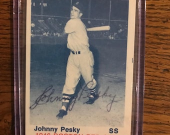 May include: A vintage baseball card featuring Johnny Pesky of the 1946 Boston Red Sox. The black and white image shows Pesky in his baseball uniform, mid-swing. The card is encased in a protective plastic sleeve.