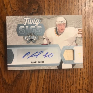 Puede incluir: Una tarjeta de hockey con Pavel Bure, un ex jugador de la NHL. La tarjeta es de la serie "Twig Sigs Lumber". La tarjeta tiene un fondo azul y plateado con una imagen de Bure con su uniforme de los Canucks de Vancouver. La tarjeta también presenta la firma de Bure en tinta azul.
