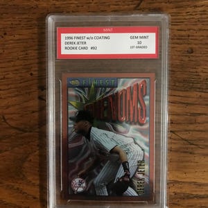 Może przedstawiać: Karta debiutanta Dereka Jeter z 1996 Topps Finest, oceniona na 10, czyli najwyższą możliwą ocenę, w plastikowym etui. Karta przedstawia kolorowe zdjęcie Jeter w mundurze New York Yankees.