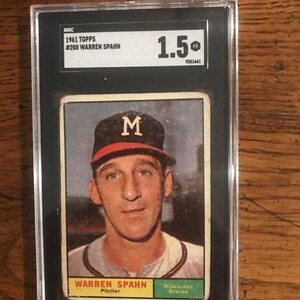 以下が含まれることがあります： 1961年のトップスベースボールカード。ミルウォーキー・ブレーブスの投手、ウォーレン・スパーンが描かれています。SGCによって1.5と評価されており、スパーンが帽子に「M」の文字が入ったベースボールユニフォームを着ている白黒写真が掲載されています。カードは緑色の背景で、「ミルウォーキー・ブレーブス」と「ピッチャー」の文字が印刷されています。