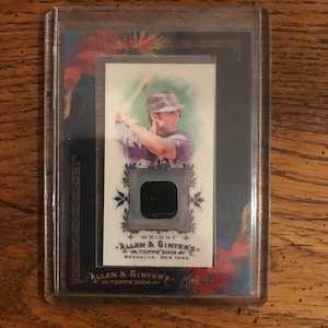 Puede incluir: Una tarjeta de béisbol con un jugador de béisbol con un uniforme morado sosteniendo un bate. La tarjeta es de la serie Allen & Ginter's Topps 2009. La tarjeta tiene una foto en blanco y negro del jugador y un parche de camiseta negro.