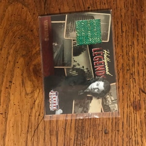 May include: A trading card featuring a black and white photo of a woman with the text "Hollywood Legends" and a green foil patch.