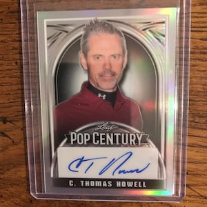 May include: A silver and black trading card featuring a portrait of C. Thomas Howell, a Leaf Pop Century card with his autograph.