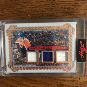 May include: A hockey card featuring a player in a blue and orange uniform with a gold border. The card has a paint-by-numbers theme and the text "Paint by Numbers" and "1987 Career Points".