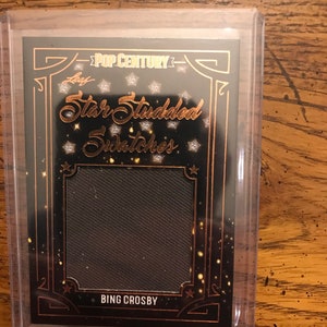 May include: A black and gold trading card with the text "Pop Century" and "Star Studded Swatches" in gold lettering. The card features a black fabric swatch and the name "Bing Crosby" in gold lettering.