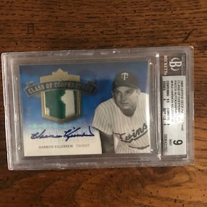Könnte beinhalten: Eine Baseballkarte mit einem Foto von Harmon Killebrew, einem ehemaligen Spieler der Minnesota Twins. Die Karte ist von Beckett Grading Services mit einer 9 bewertet und enthält ein Patch-Autogramm von Killebrew. Die Karte ist Teil des 2005 Upper Deck Hall of Fame Class of Cooperstown Sets.