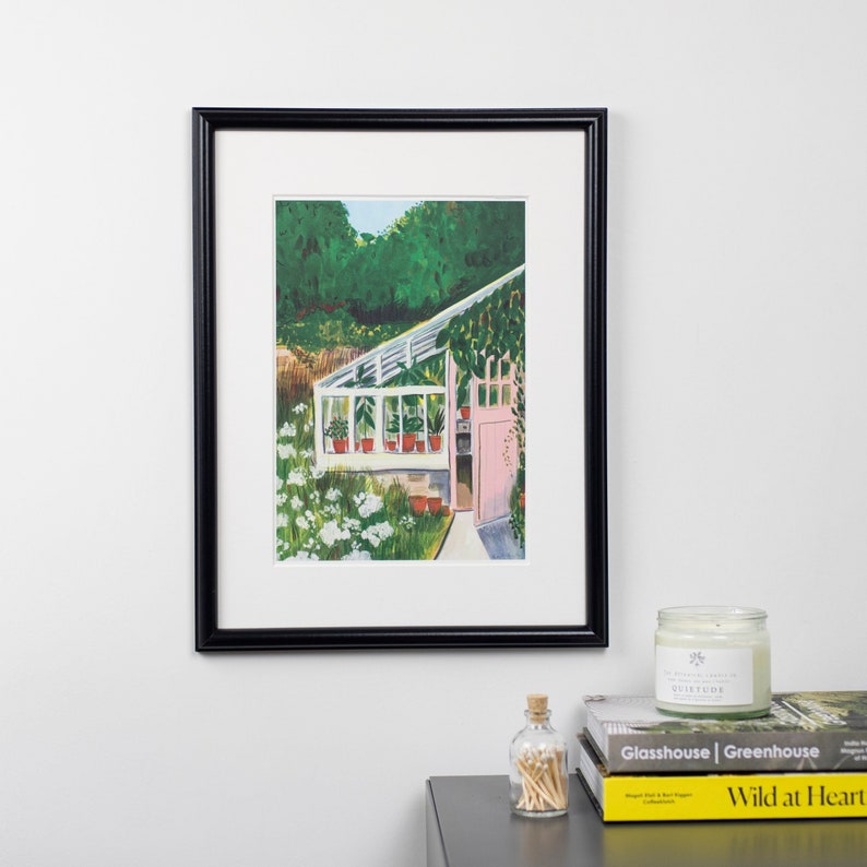 May include: A framed painting of a greenhouse with a pink door and lush green plants. The greenhouse is surrounded by white flowers and a green forest in the background.