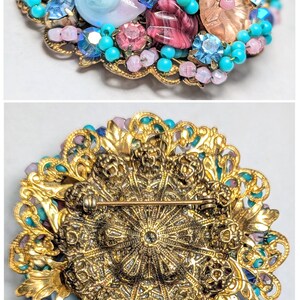 May include: A vintage brooch with a gold filigree design and a cluster of pink, blue, and turquoise beads and glass stones.