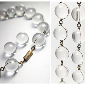 May include: A clear glass beaded necklace with a gold clasp. The beads are round and have a smooth, polished finish.