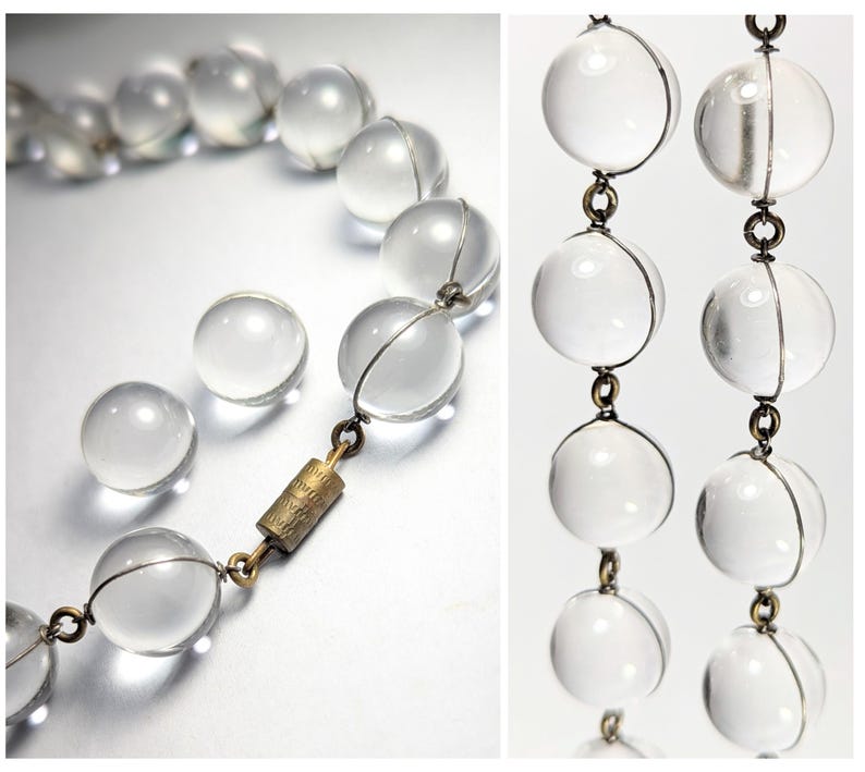 May include: A clear glass beaded necklace with a gold clasp. The beads are round and have a smooth, polished finish.