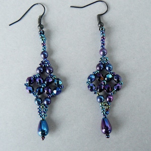 May include: A pair of long dangle earrings featuring dark blue and purple iridescent beads. The design includes faceted crystals and small seed beads arranged in a geometric pattern, finished with a single teardrop-shaped bead at the bottom.
