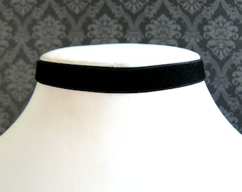 Puede incluir: Un collar gargantilla de terciopelo negro sobre un maniquí de busto blanco.