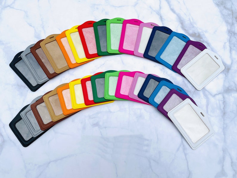 May include: A collection of 20 colorful badge holders, each with a clear plastic window for displaying identification cards. The holders are made of a soft, textured material and come in a variety of bright colors, including red, orange, yellow, green, blue, purple, pink, and white.