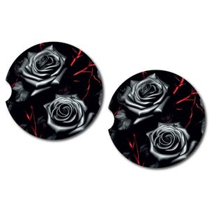 May include: Two black and white round coasters with a design of black roses and red vines on a black background.