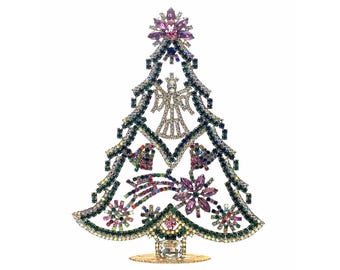 May include: A decorative Christmas tree figurine, adorned with colorful rhinestones. The tree features a star topper, an angel, and various ornaments. The base is gold-toned, and the overall design is festive and sparkly.