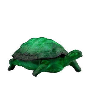 Puede incluir: Una figurita de tortuga de vidrio verde con una concha detallada y un acabado liso y pulido.