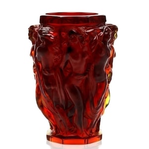 Könnte beinhalten: Eine rote Glasvase mit einem Reliefdesign aus mehreren Figuren. Die Vase ist aus klarem Glas mit einer roten Tönung.