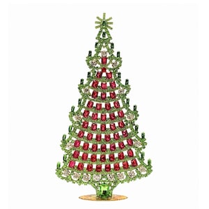 Op de afbeelding: Een decoratief kerstboomfiguur. De boom is versierd met groene, rode en heldere kristallen. De boom heeft een ster op de top en staat op een goudkleurige basis. Een feestelijke vakantiedecoratie.