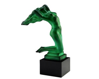 May include: A green glass sculpture of a woman with flowing hair, standing on a black base.