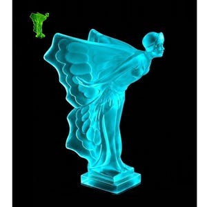 Op de afbeelding: Een doorschijnend cyaan glazen beeldje van een figuur met uitgestrekte armen en grote, vleugelachtige draperieën, staand op een rechthoekige voet. Een kleinere, groen getinte versie van hetzelfde beeldje is zichtbaar in de linkerbovenhoek.