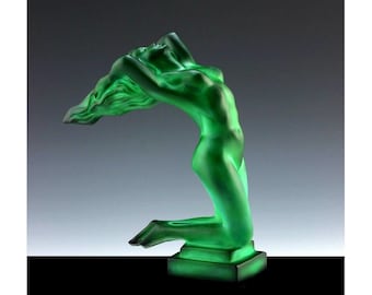 Puede incluir: Una escultura de vidrio verde de una mujer con los brazos levantados por encima de su cabeza. La escultura está en posición de rodillas y tiene un diseño fluido y abstracto.