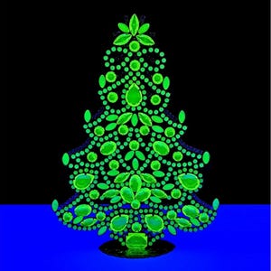 Puede incluir: Un árbol de Navidad decorativo con una base negra y un diseño verde vibrante. El árbol está adornado con numerosas gemas verdes y acentos circulares, creando un efecto brillante sobre un fondo negro y azul.