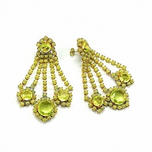 May include: A pair of dangle earrings with multiple tiers of yellow rhinestones. The earrings feature a large, round, yellow rhinestone at the bottom of each dangle.