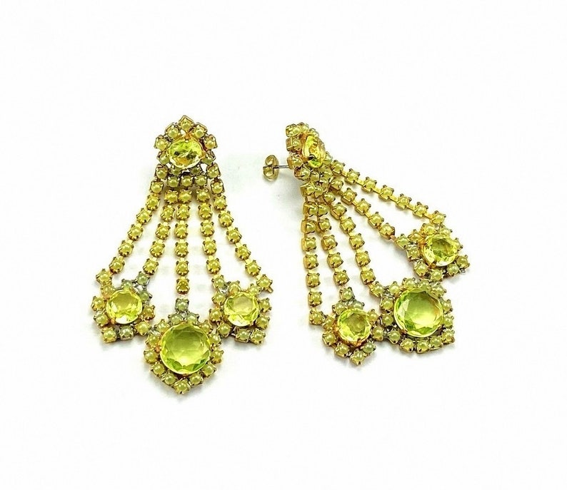 May include: A pair of dangle earrings with multiple tiers of yellow rhinestones. The earrings feature a large, round, yellow rhinestone at the bottom of each dangle.