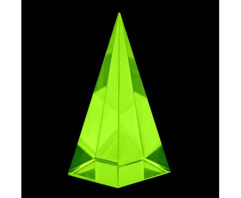 May include: A neon green, geometric pyramid-shaped object. The pyramid has a flat base and sharply angled sides that converge at a point. The object is made of a translucent material and is set against a black background.