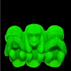 May include: A neon green sculpture of three monkeys in the 'see no evil, hear no evil, speak no evil' pose. The monkeys are sitting together, with their hands covering their eyes, ears, and mouth. The background is black.