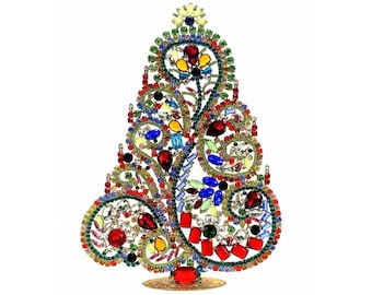 May include: A decorative tabletop tree ornament constructed from a metal frame encrusted with multicoloured rhinestones in red, blue, green, yellow, and clear. The design features swirling filigree patterns and a star-shaped topper on a base.