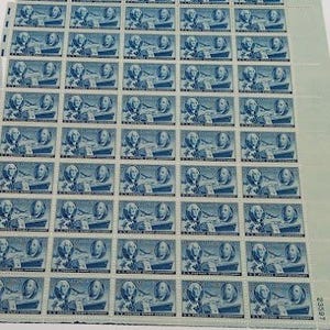 以下が含まれることがあります： ジョージ・ワシントンの肖像画と飛行機が描かれた青いU.S. Postage Stamp Centenary切手のフルシート。切手はミシン目入りのグリッド状に配置されており、余白には23597という数字が印刷されています。